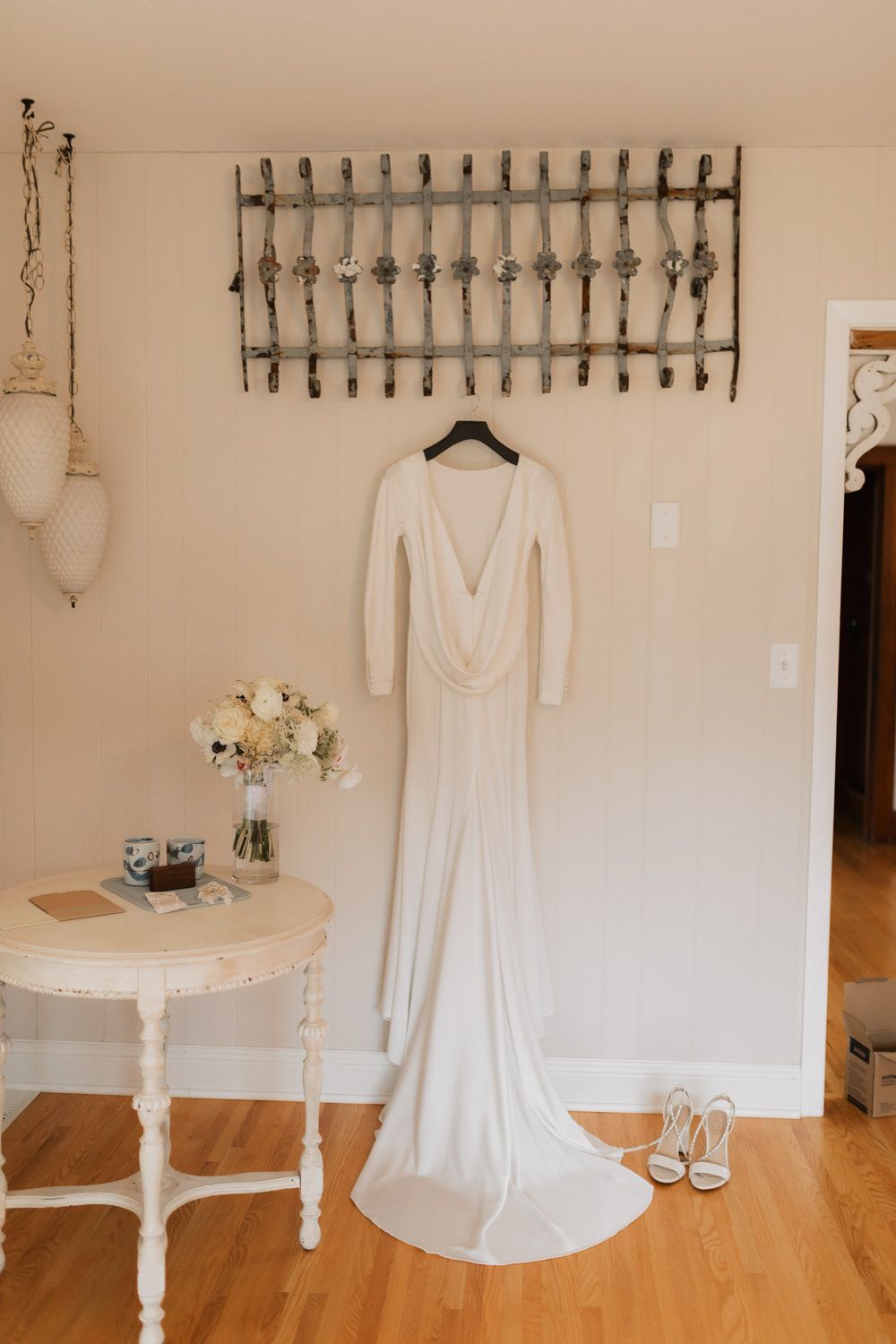 Wedding dress display in a bridal boutique with white gowns hanging elegantly against cream-colored walls.