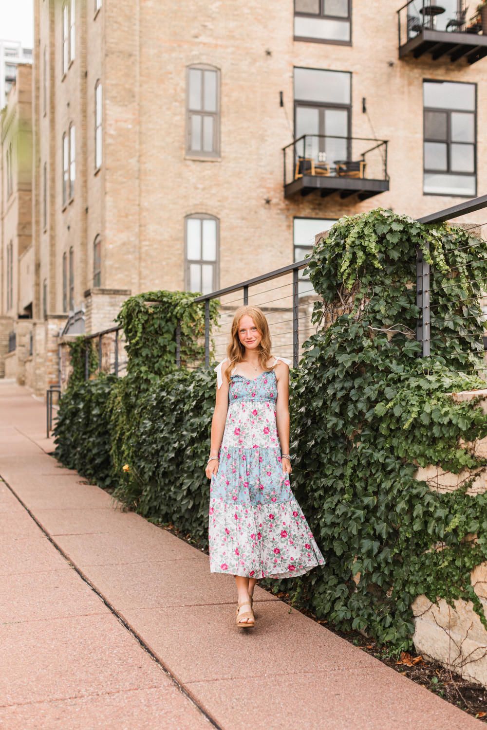 A flowing summer dress captured in motion along a stone building path with green ivy.