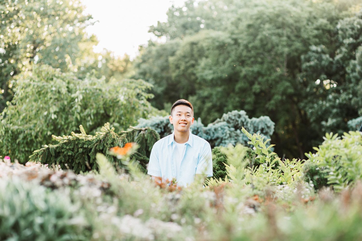 Scenic outdoor portrait amid flowering plants and natural greenery.