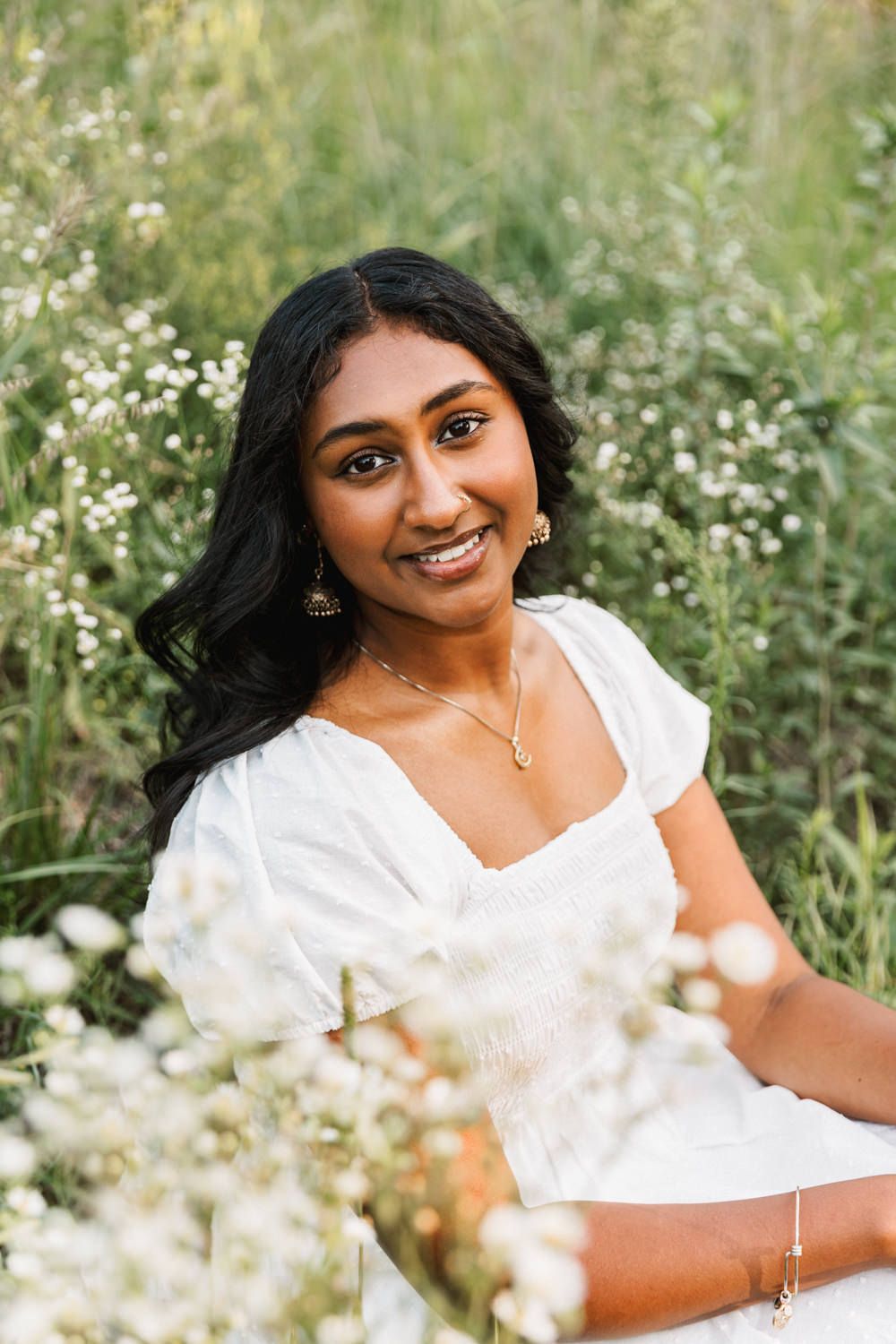 Outdoor portrait in blooming wildflower meadow wearing white dress.