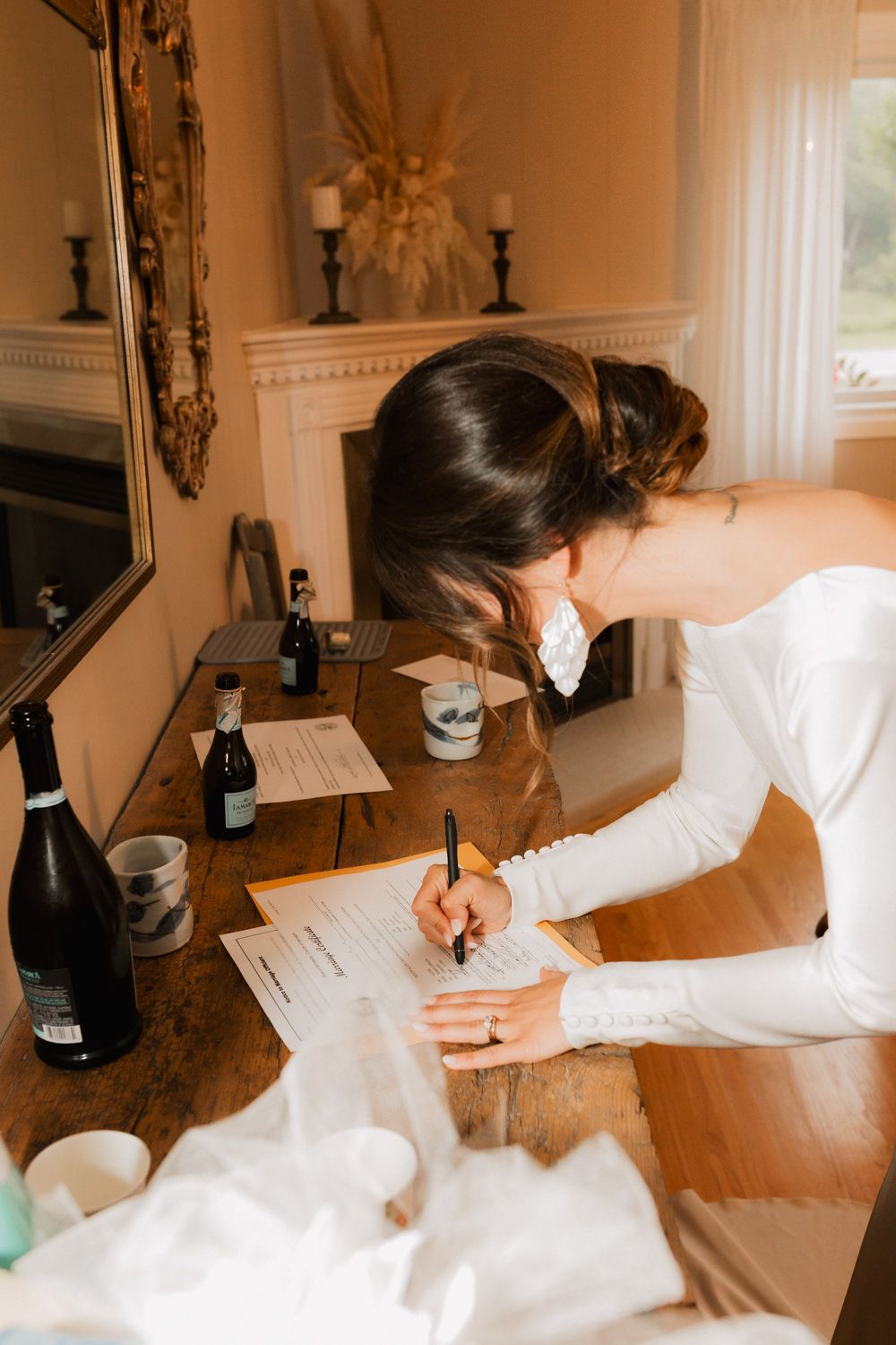 Person in white dress signing documents at an elegant wooden table.