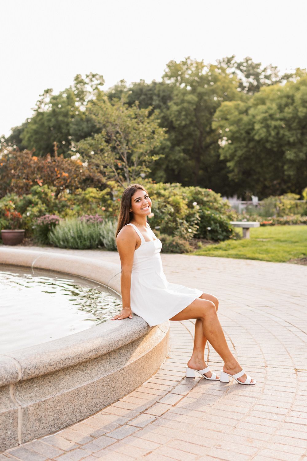 Elegant outdoor portrait session on curved stone benches near a garden water feature.