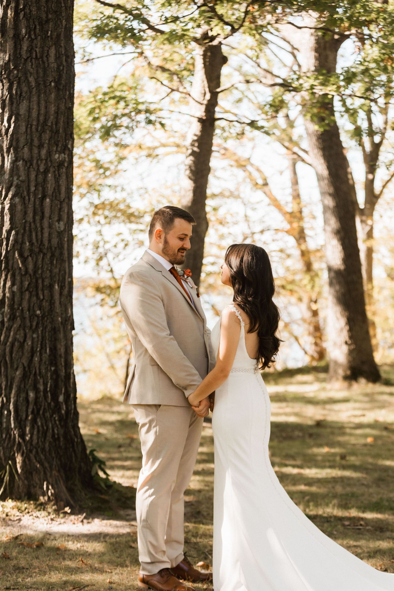 A romantic wedding couple shares intimate moments in a sun-dappled forest setting during their special day.