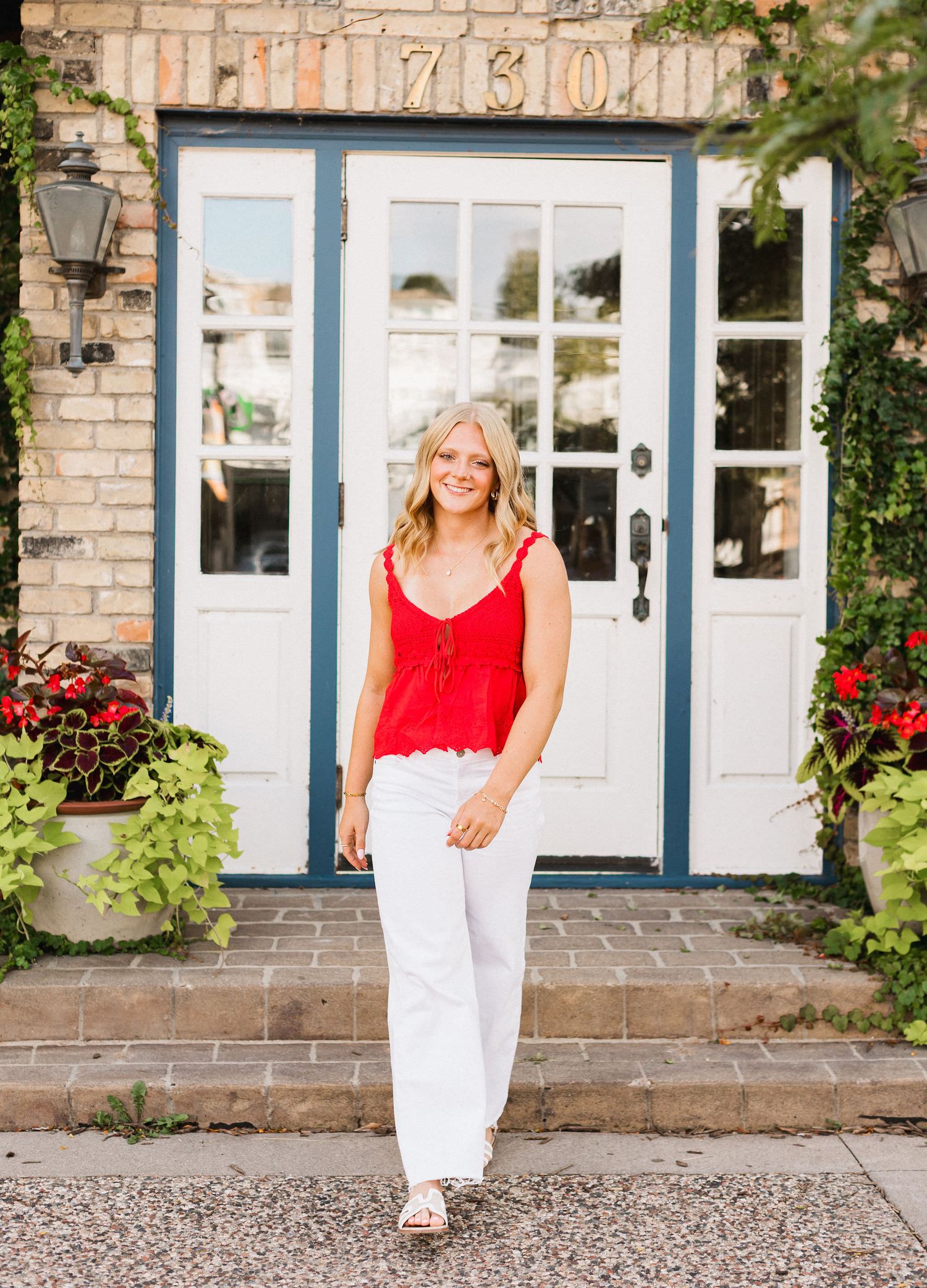 A series of four candid shots showing someone in a red top and white pants walking and posing in front of a brick house.