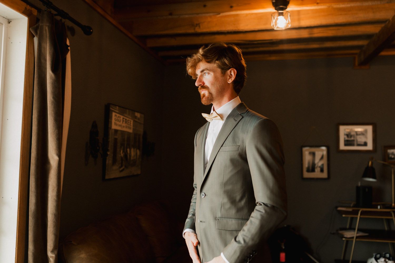 Atmospheric portrait in rustic room with wooden beams and dramatic window lighting.