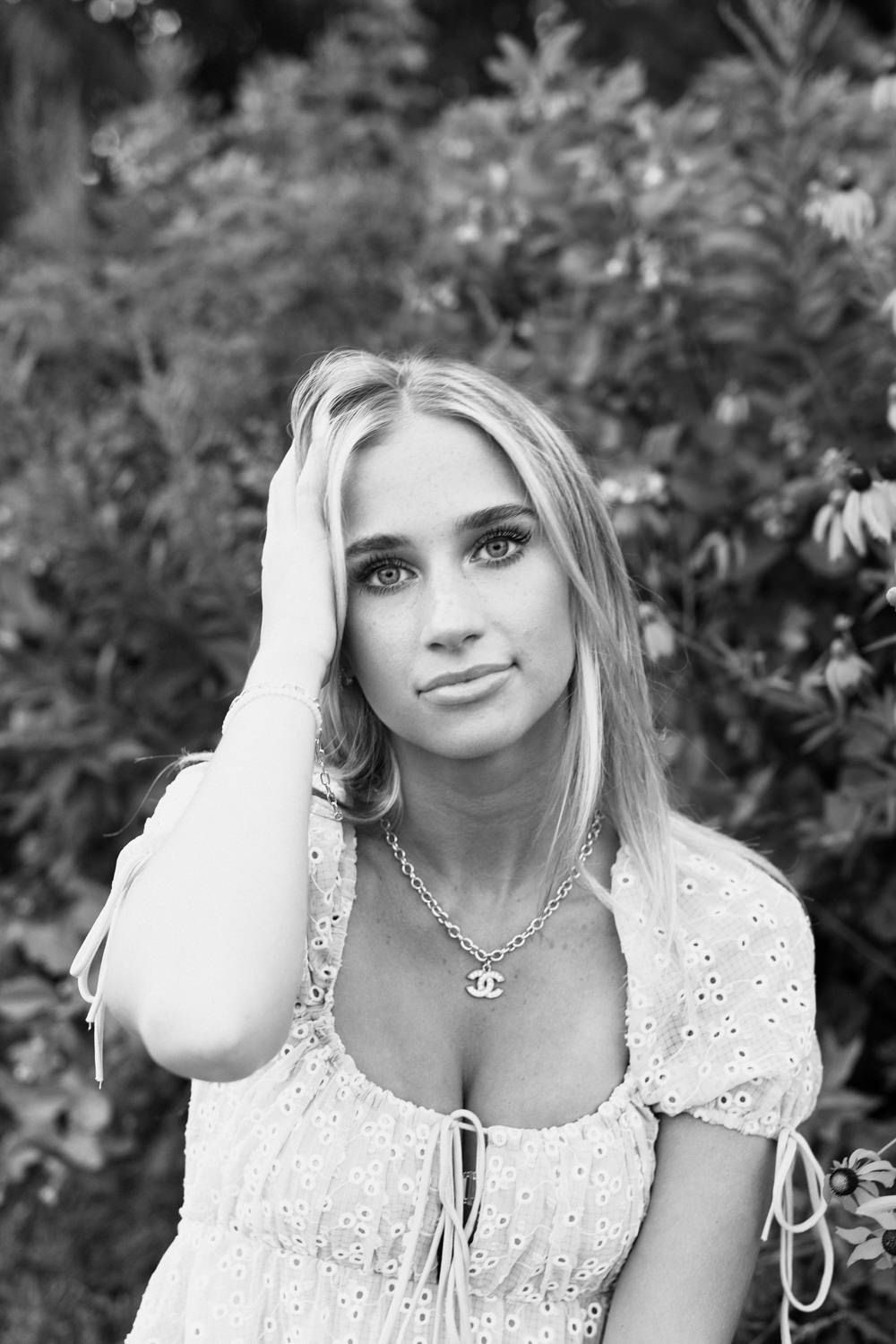 Black and white portrait wearing a white eyelet dress with dainty necklace.