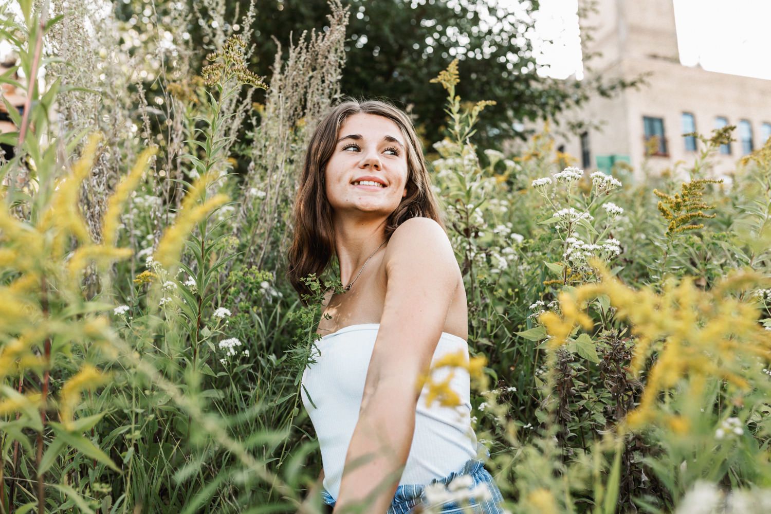 Portrait in garden setting with wild flowers and architecture in background.