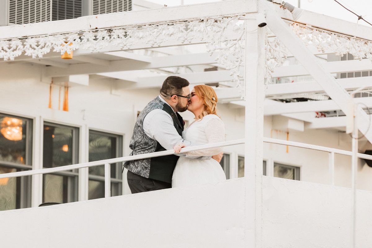 Two people work at a modern office desk with white decor and natural lighting through large windows.