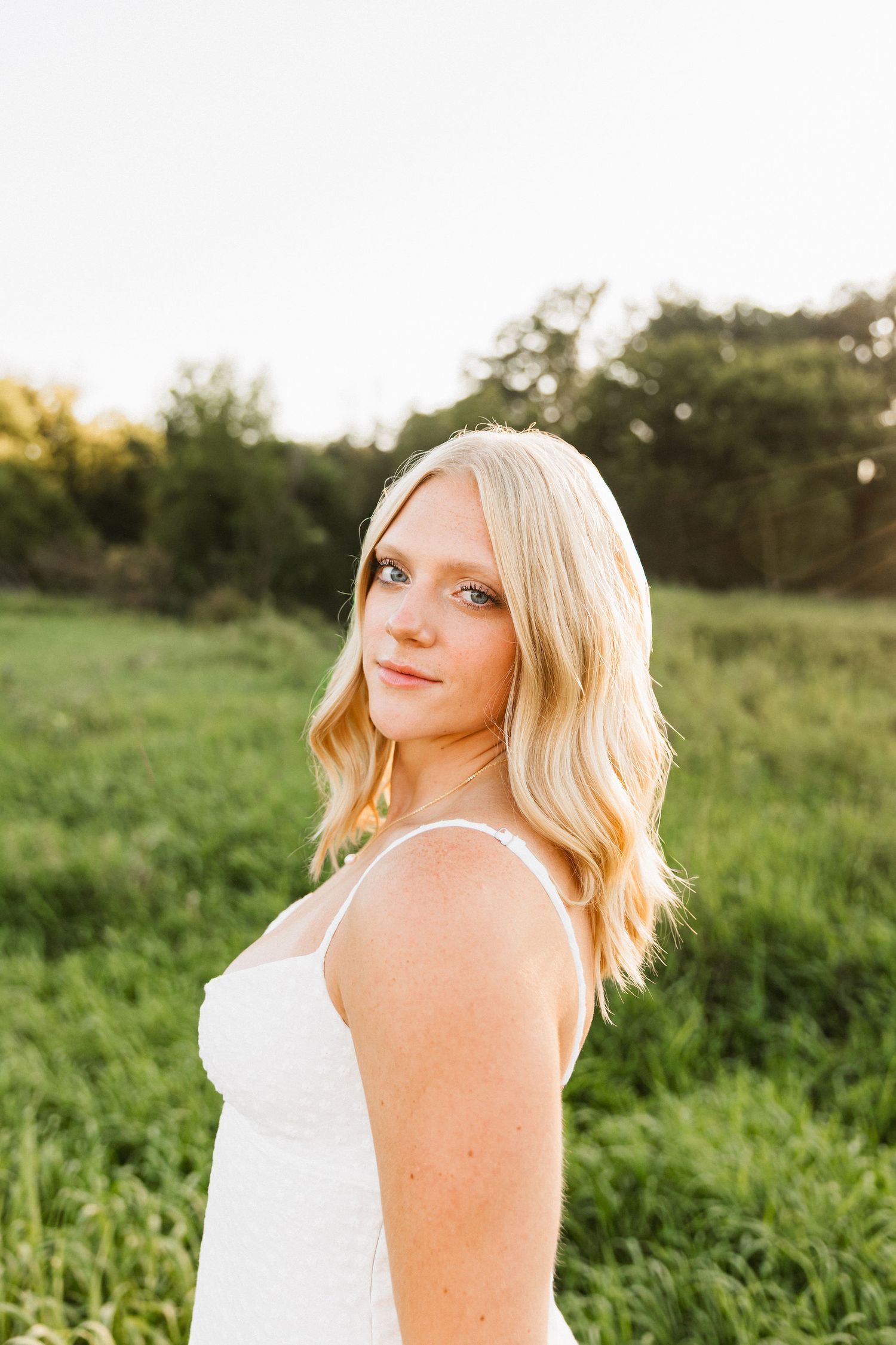 Natural light portrait photography in grassy meadow at sunset.