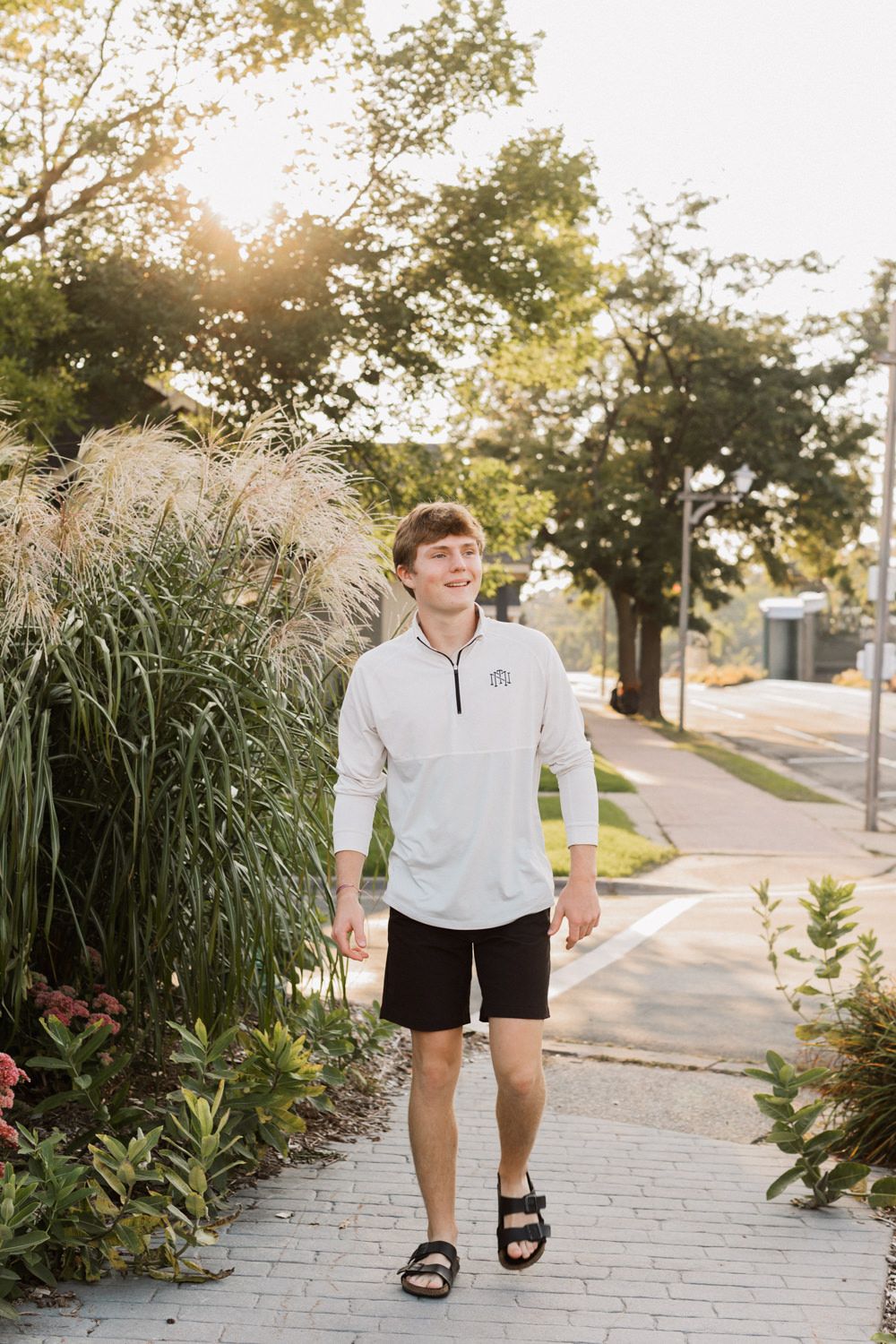 Individual in activewear walks along a landscaped pathway with ornamental grasses and flowers.