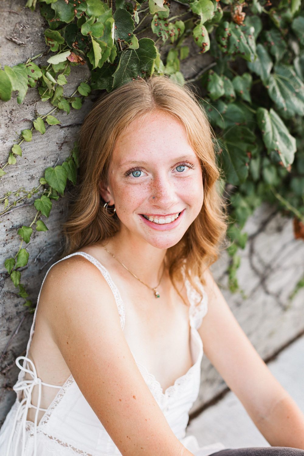A summery portrait session against lush green ivy covered wall.