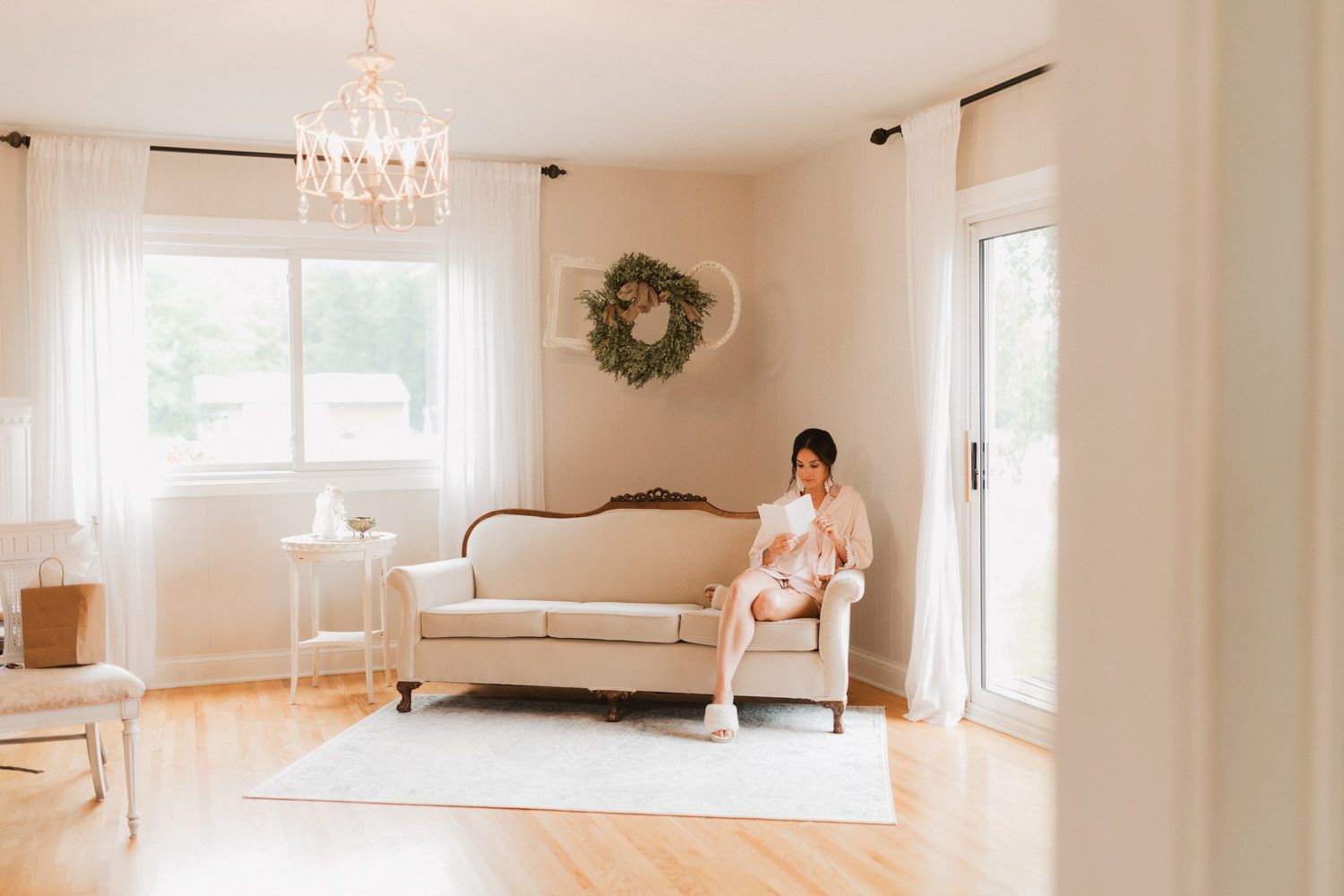 Bright white farmhouse interior room with crystal chandelier and large windows.