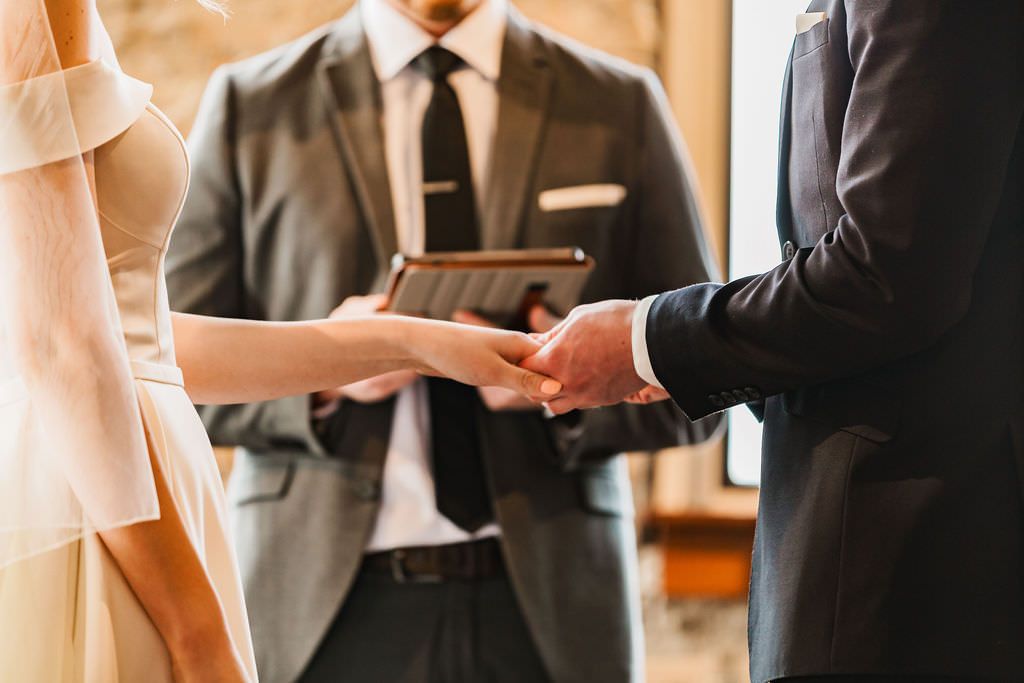 Hands holding papers during wedding ceremony readings.