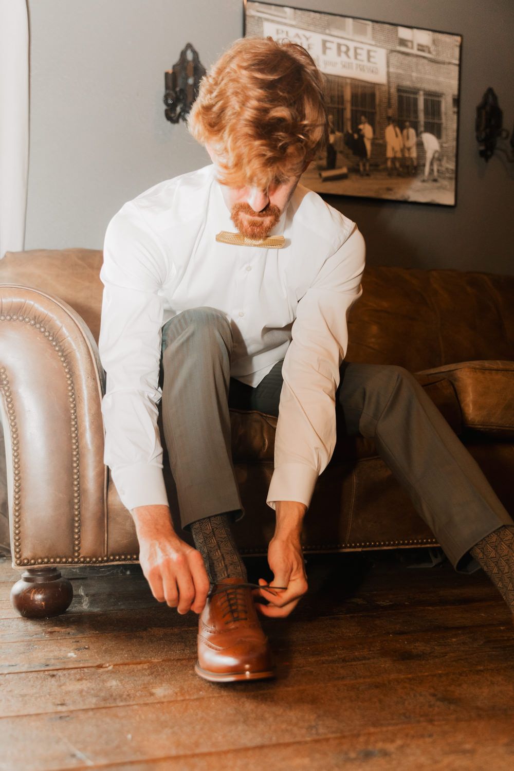 Close-up of hands polishing brown leather dress shoes on a wooden table.