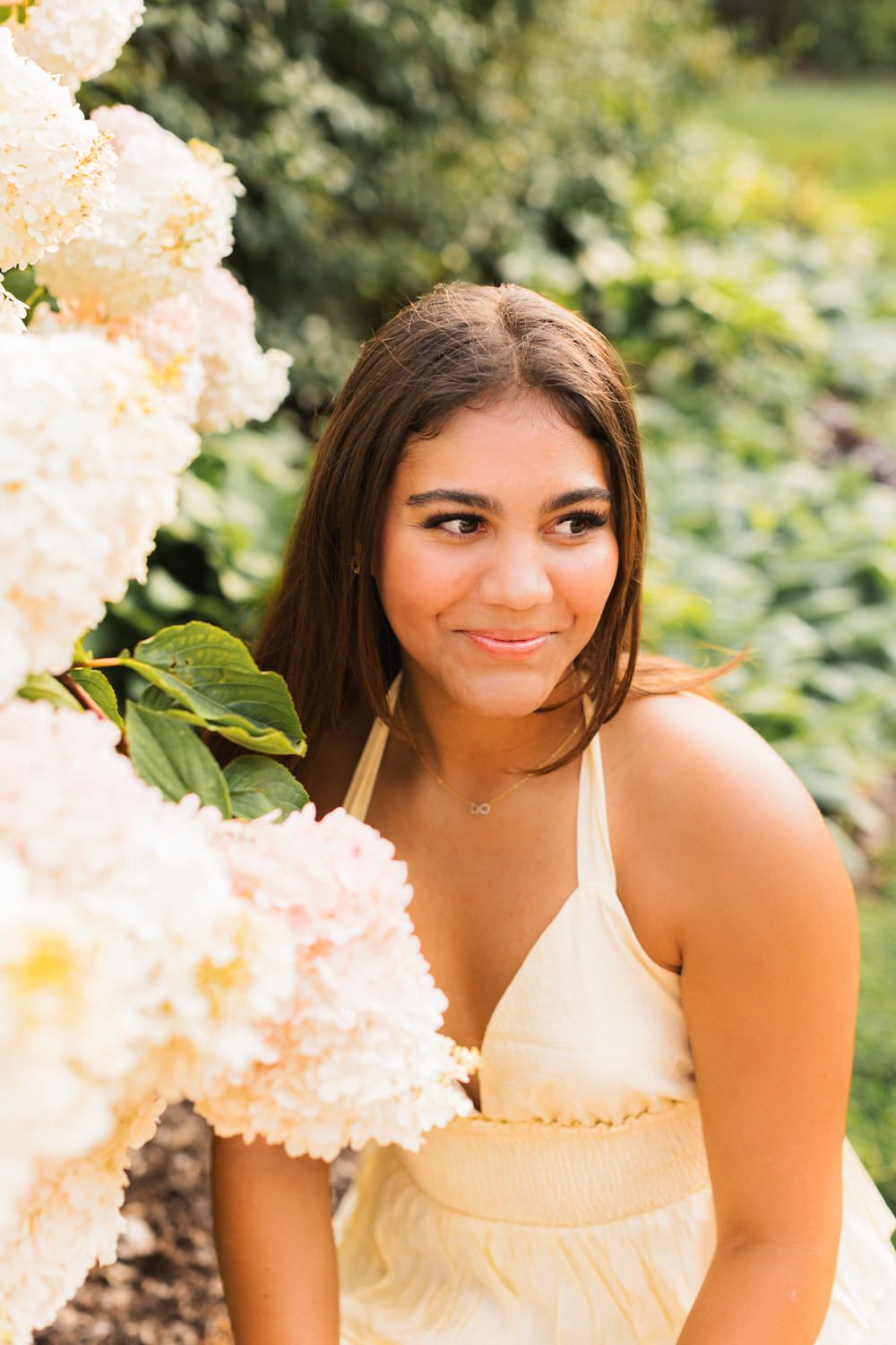 Portrait in yellow dress with white hydrangea flowers in soft natural lighting.
