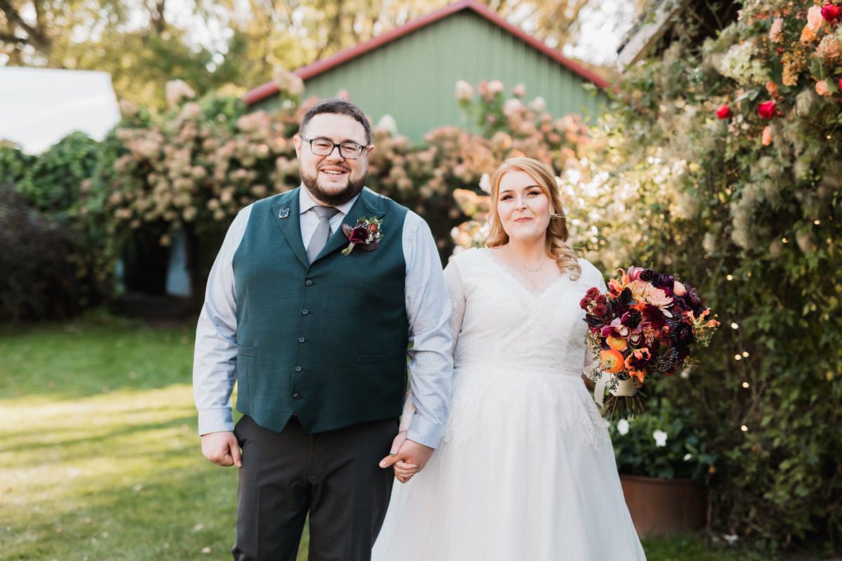 Elegant wedding portraits captured in a garden setting with blooming roses and natural greenery.