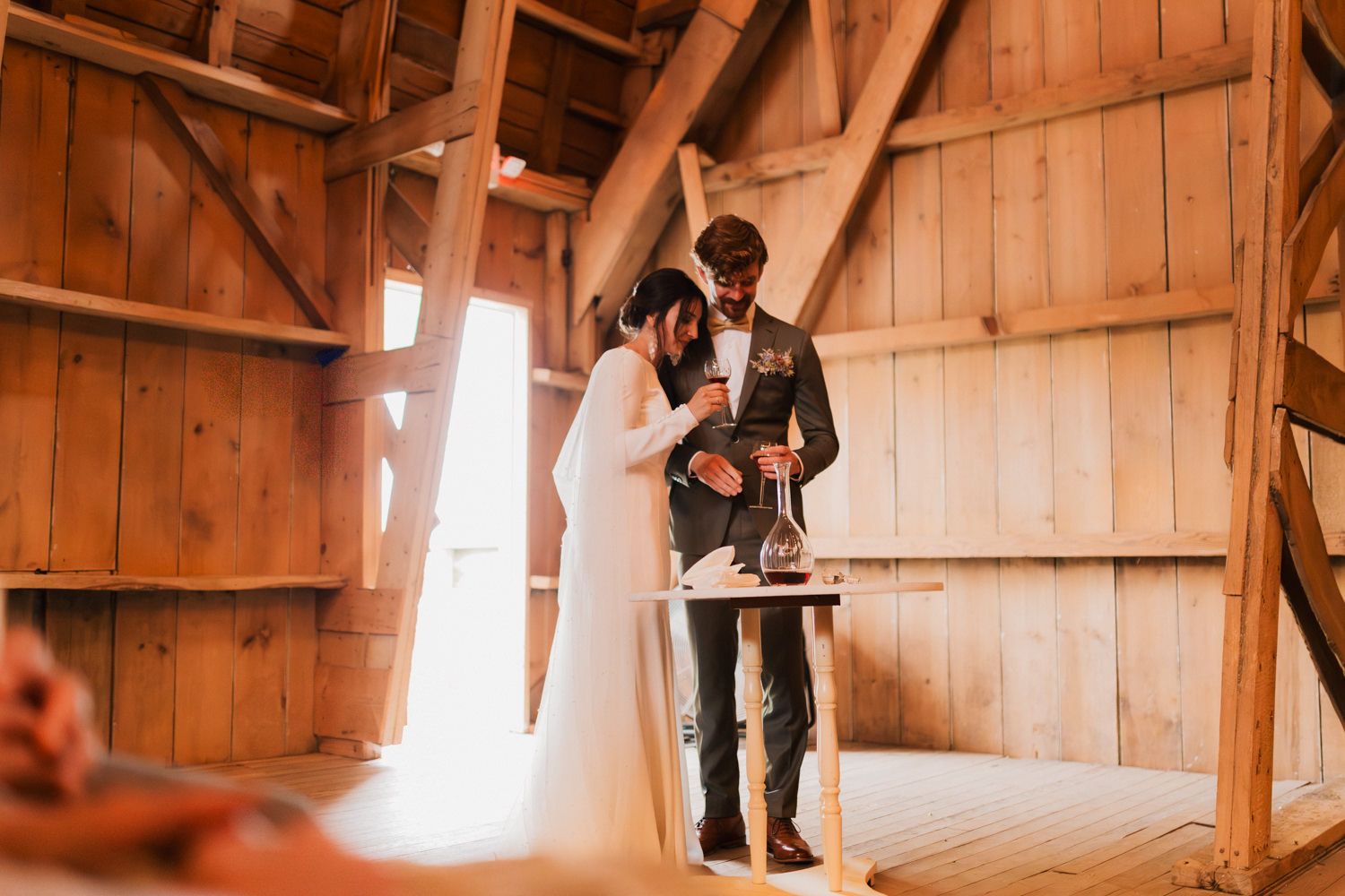 A series of candid wedding moments captured in a sunlit rustic barn setting with wooden beams.