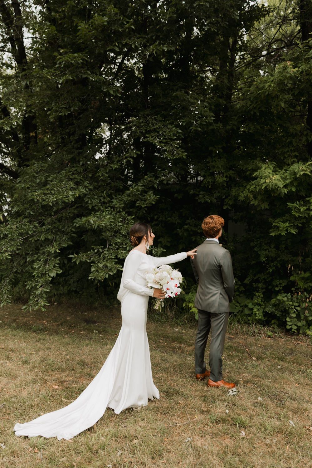 A couple shares a private first look moment before their wedding ceremony in a wooded outdoor setting.