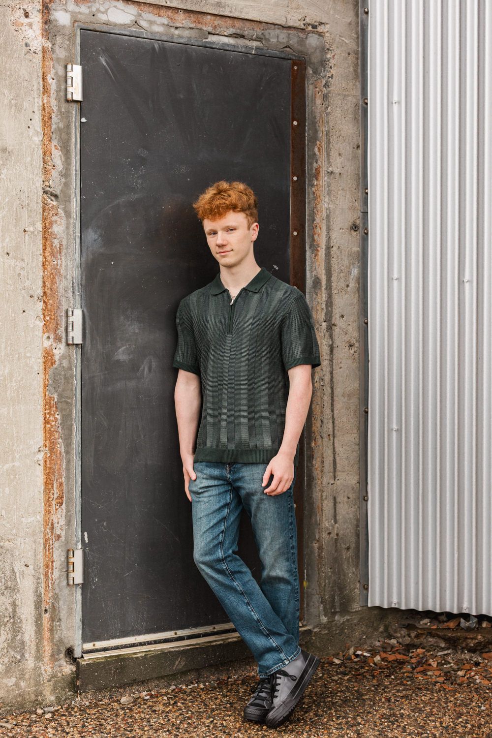 Casual portrait against industrial metal door and concrete wall background.