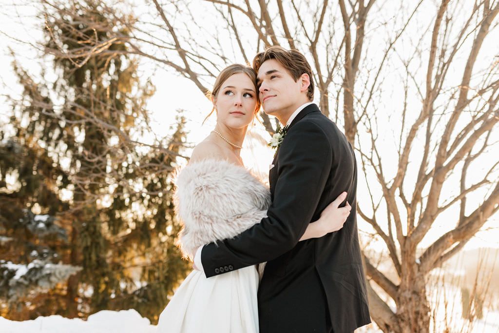 Winter wedding photograph taken outdoors with bare trees and natural lighting in the background.
