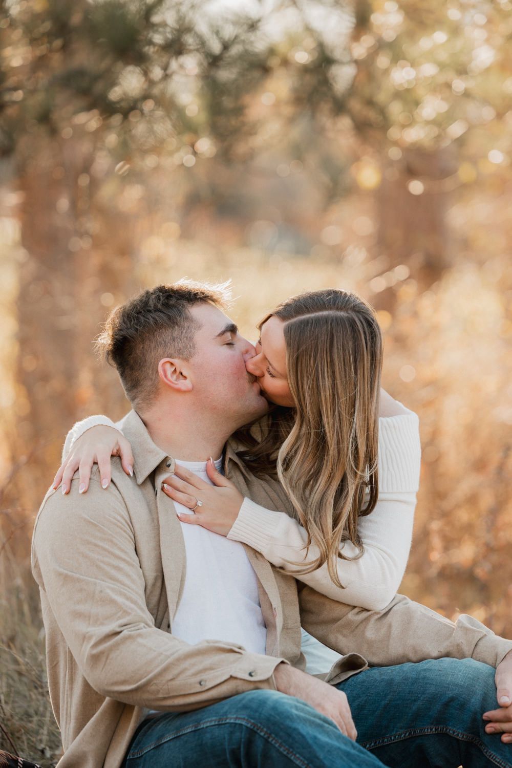 Tender moments between a couple on a blanket surrounded by golden sunlit trees.