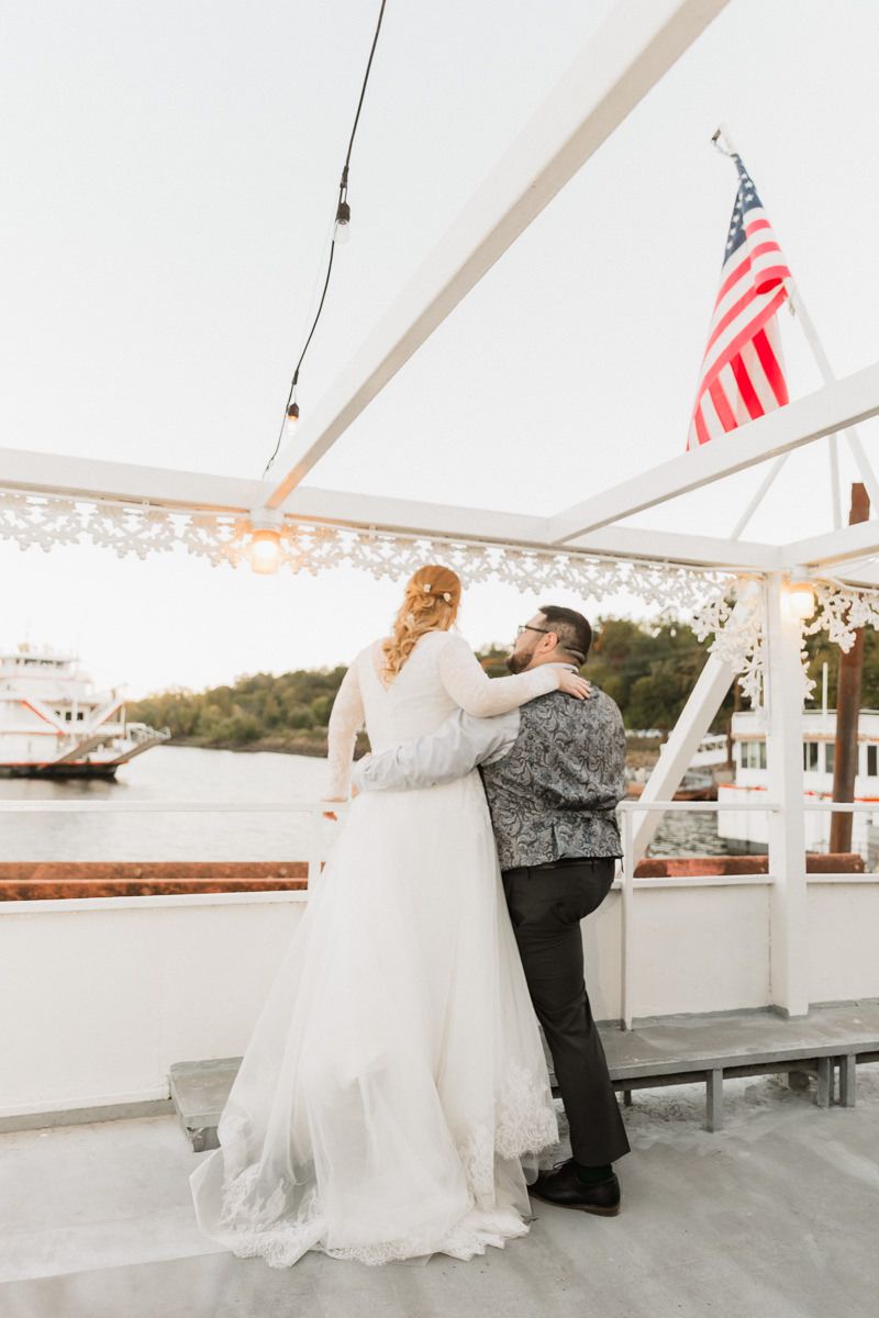 Dancing couple on boat deck with American flag waving in background at sunset.