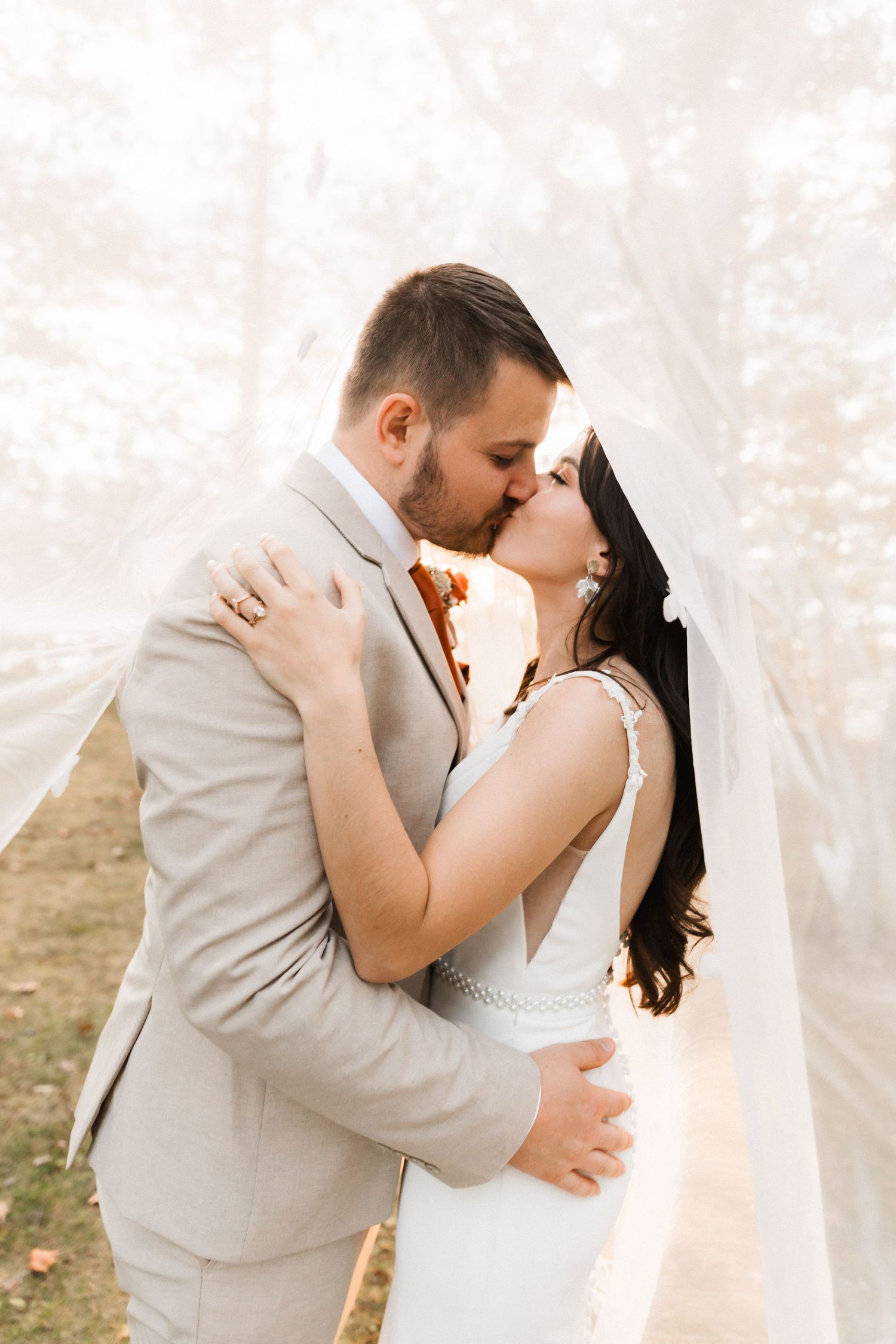 Intimate wedding portraits show tender moments between newlyweds against a bright natural backdrop.