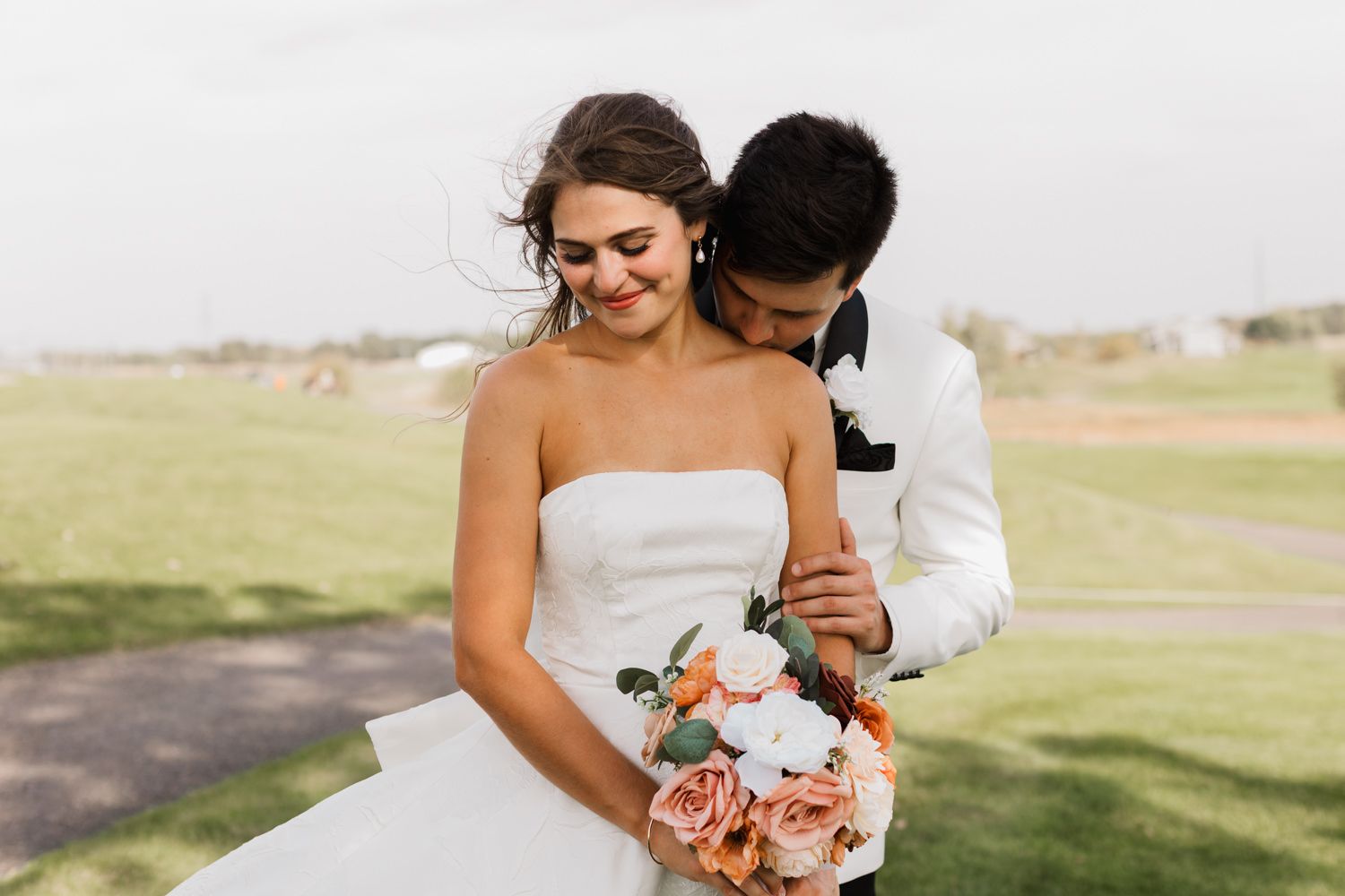 A couple embraces during their wedding photoshoot in a scenic outdoor setting with soft natural lighting.