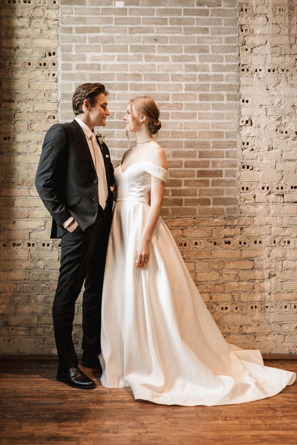 A romantic wedding photo sequence showing a couple in elegant black suit and white gown against an exposed brick wall.