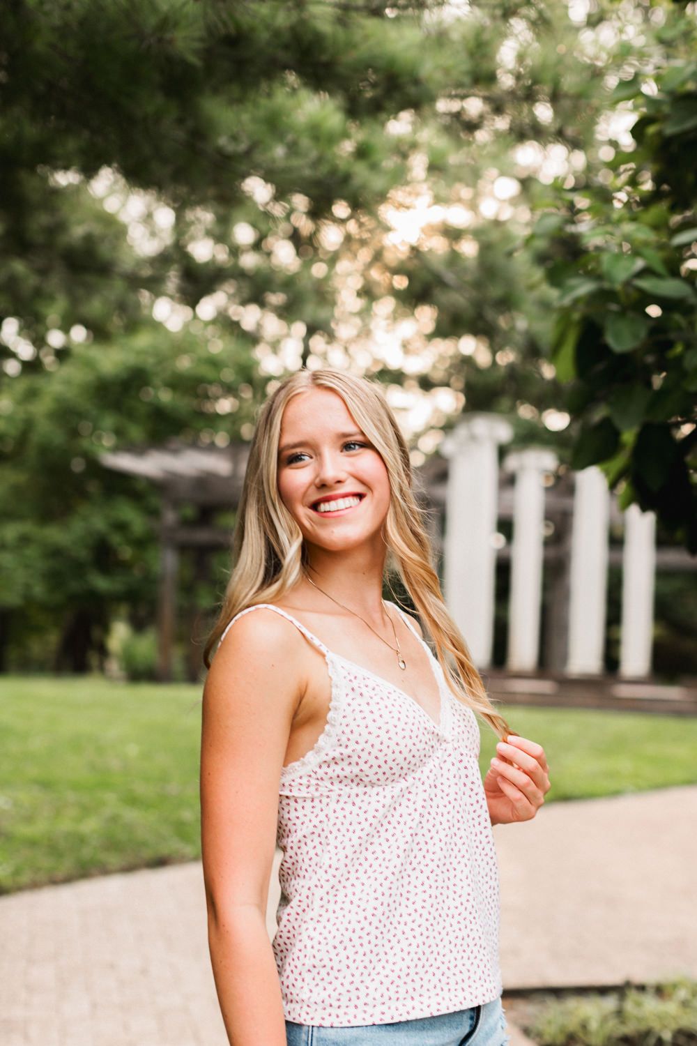 A casual summer portrait captured outdoors with bokeh lighting and architectural columns in the background.