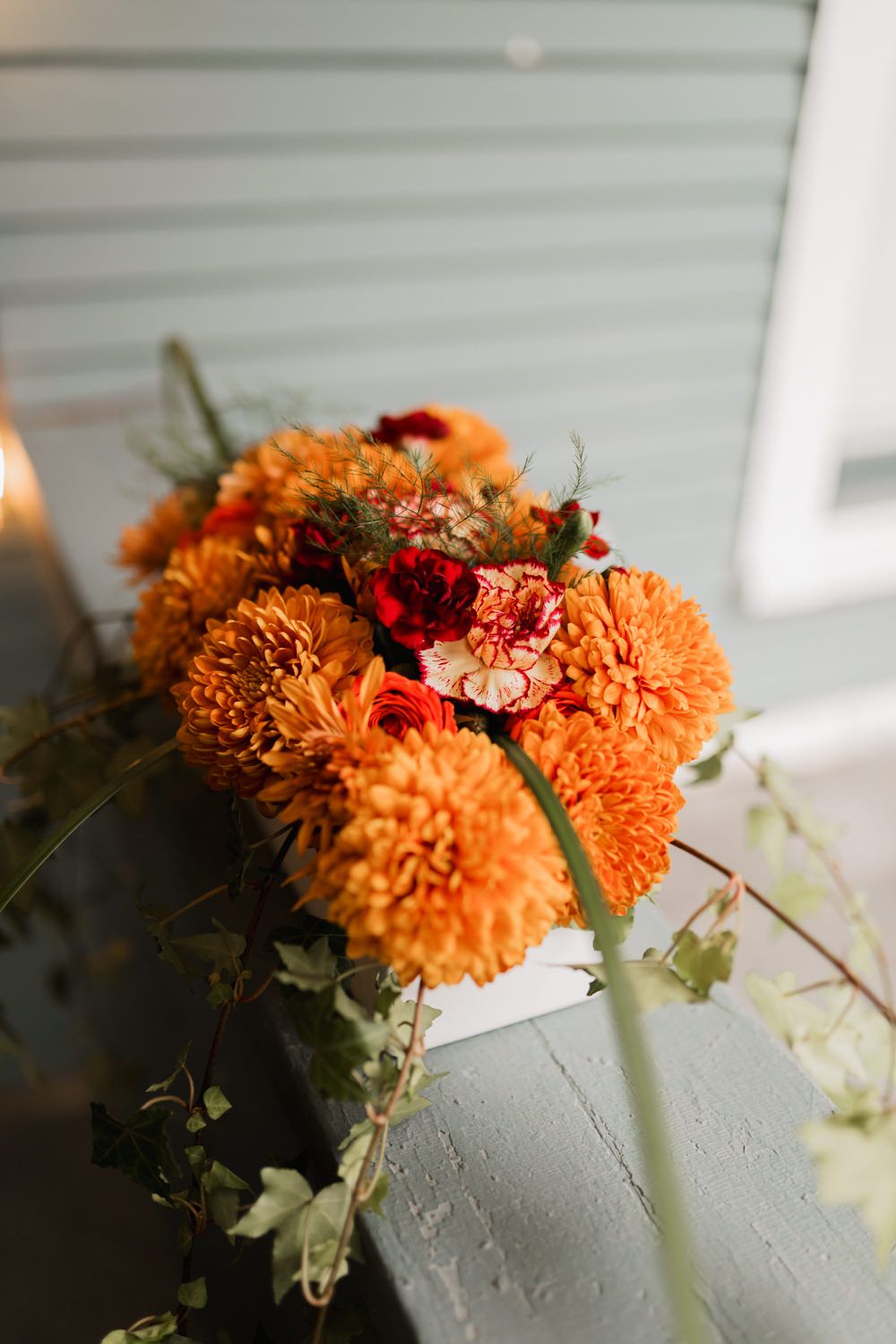Orange chrysanthemum flowers with red accents arranged in a soft natural light against a white background.