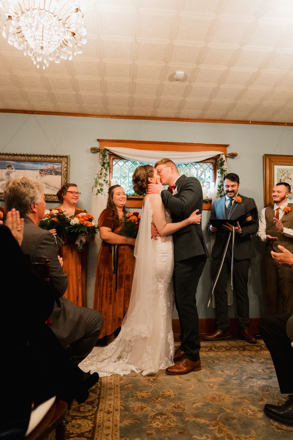 Wedding ceremony inside a rustic venue with chandelier and wooden details as guests celebrate.