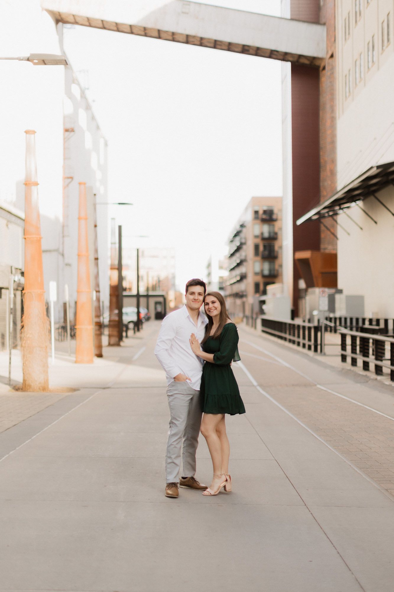 Happy couple posing together on a sunny urban street, woman wearing a green dress.