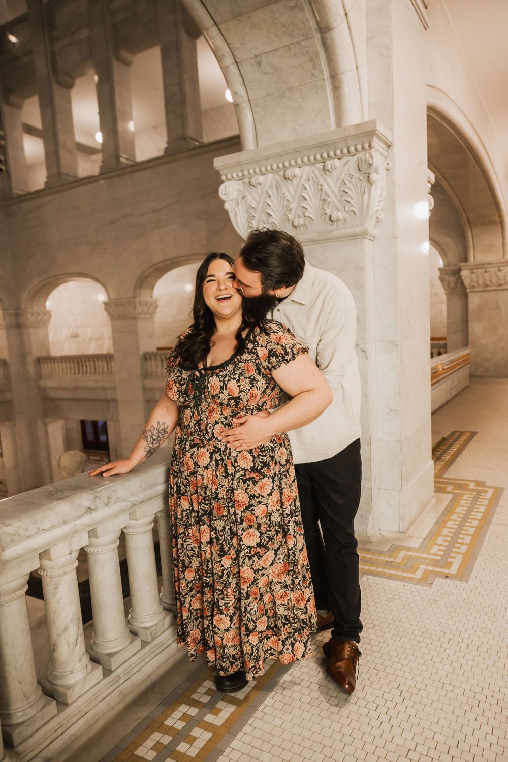 Dancing couple in formal attire twirling and laughing in a historic building with ornate columns.