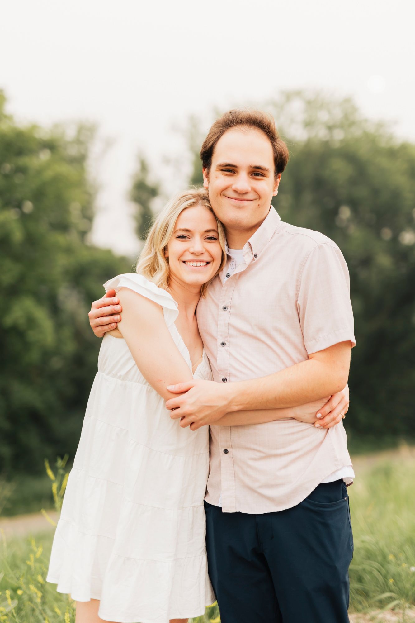 Joyful couple embracing outdoors in casual attire against a green background.