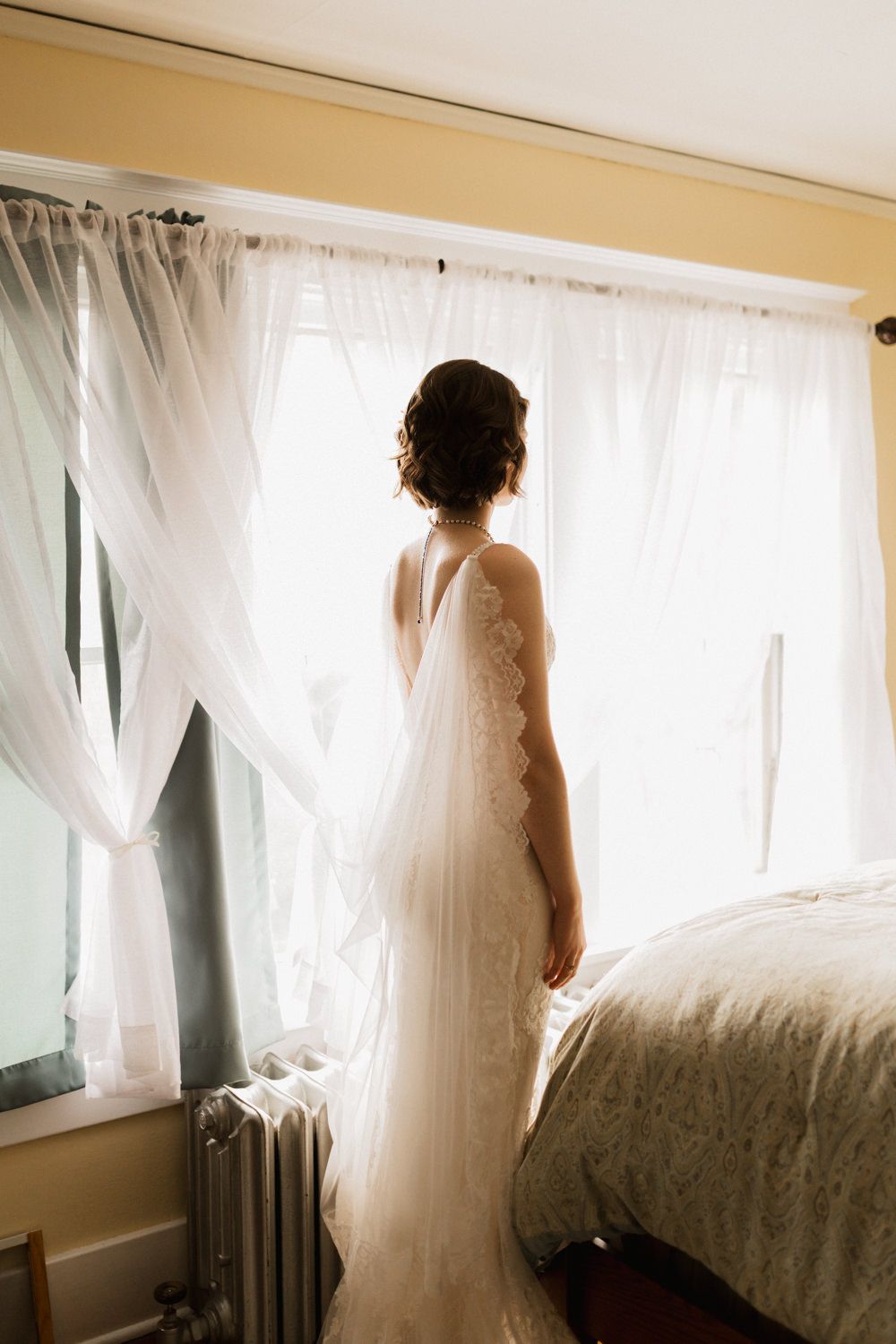 Sunlit bridal silhouettes against sheer white curtains in sequence of elegant poses.