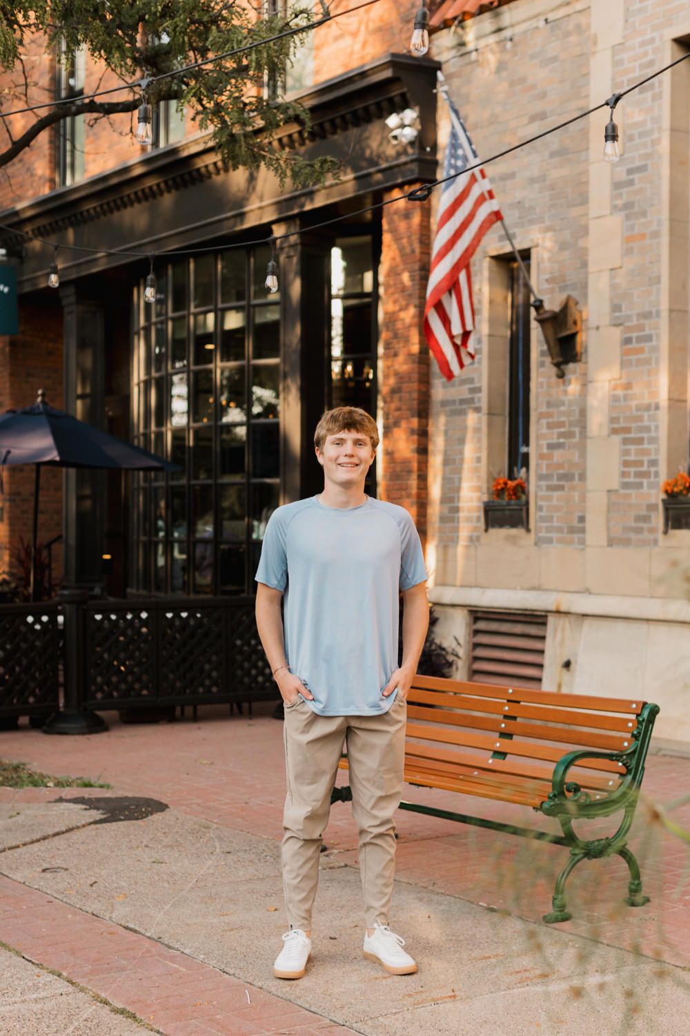 Outdoor lifestyle shots along a historic brick storefront with American flags and wooden benches.