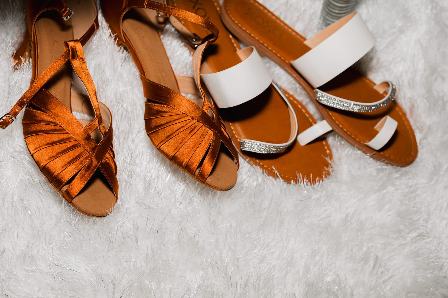 A row of brown leather dance shoes with fringe details arranged on a white textured surface.