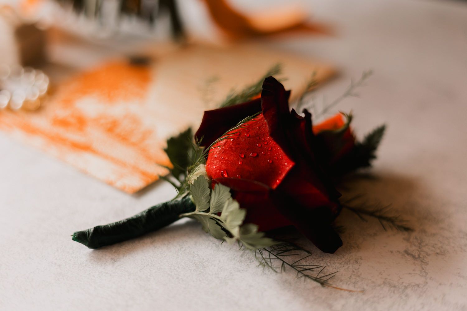 Fresh strawberries and green leaves arranged in a minimalist composition on a light surface with soft orange tones.