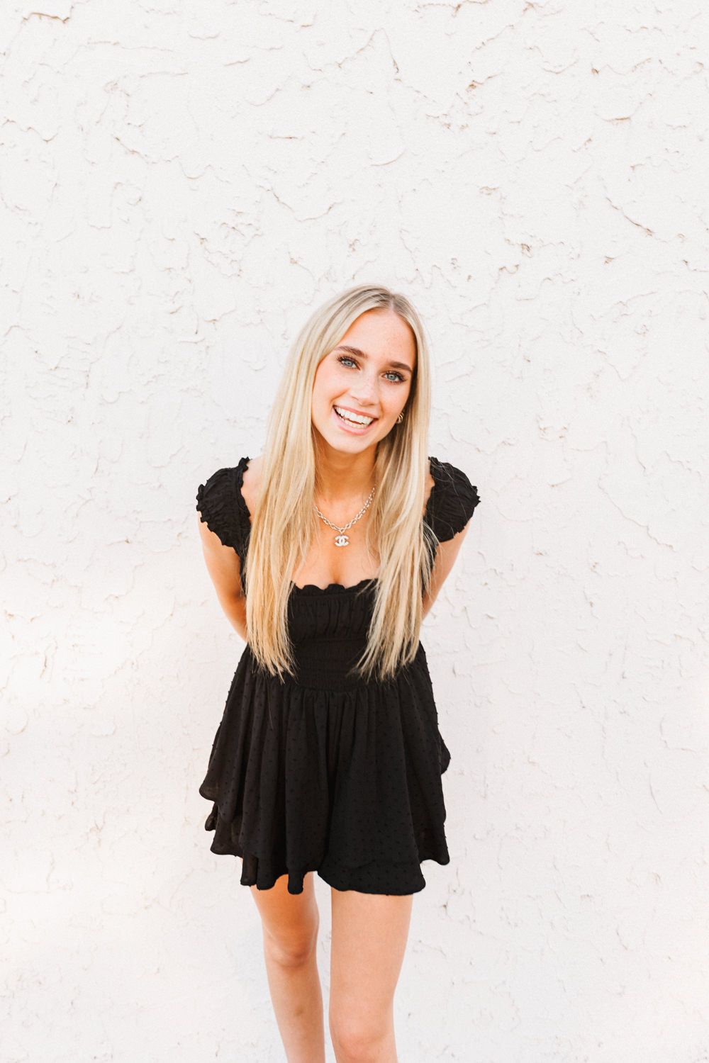 Contemporary portrait session against minimalist white wall with black ruffle dress.