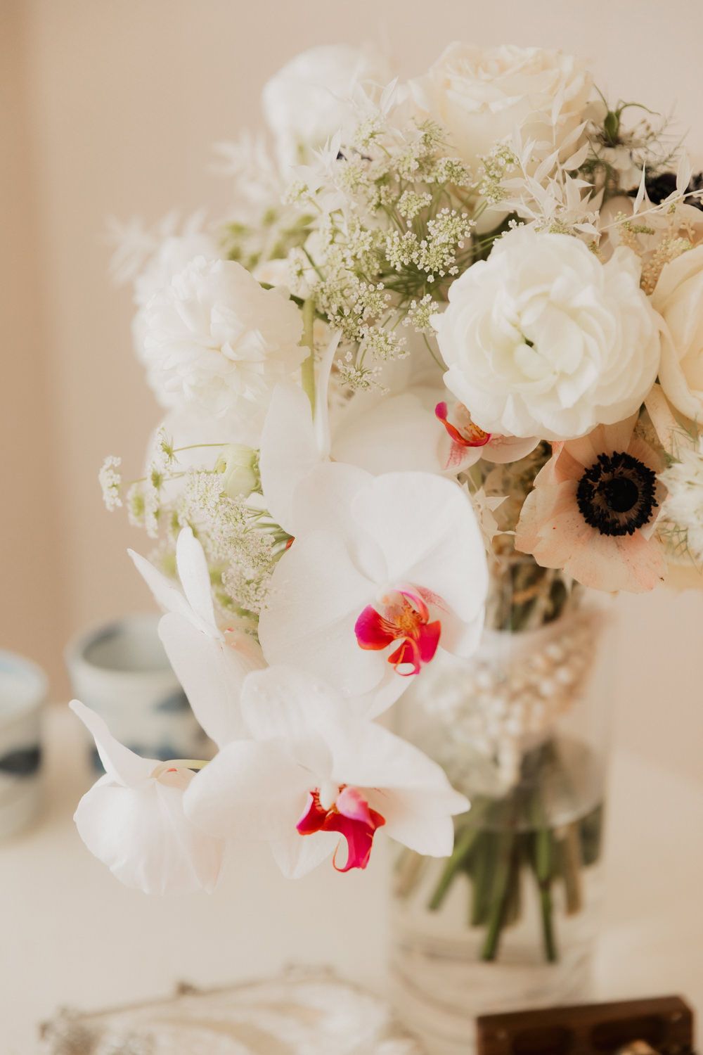 White floral arrangements with pink accents in glass vases against a neutral wall.