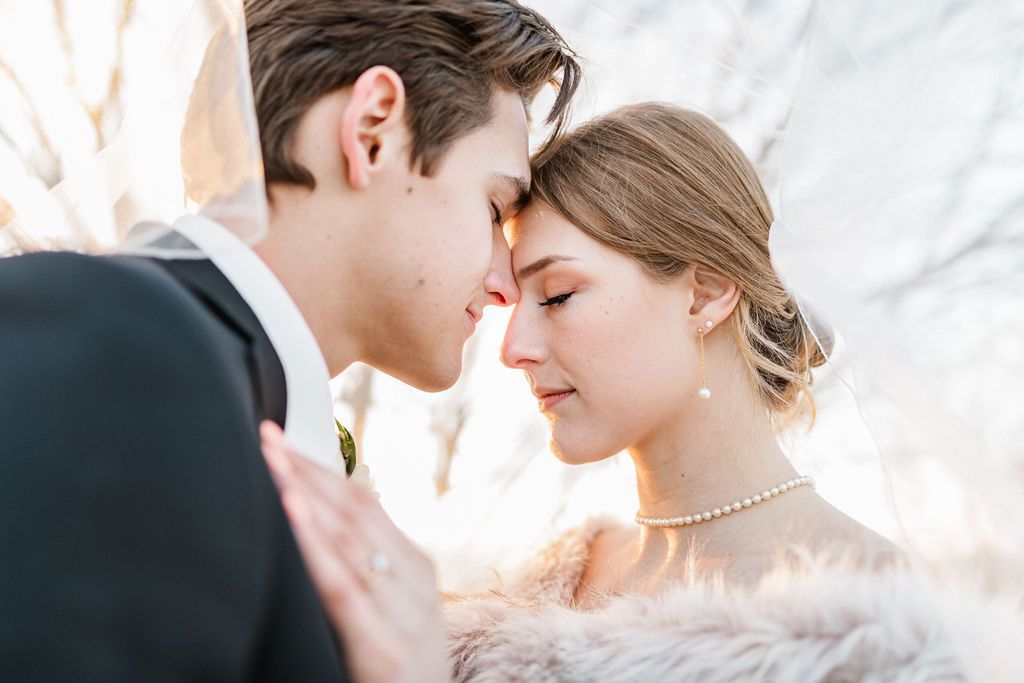 Elegant close-up wedding portrait showing romantic moment with pearl necklace detail.