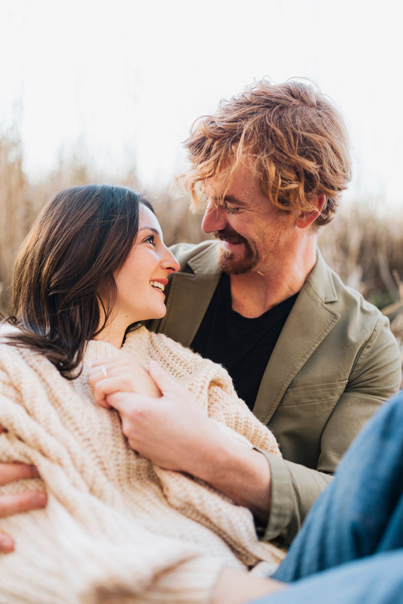 A romantic couple shares an intimate moment while wrapped in a cozy cream sweater.