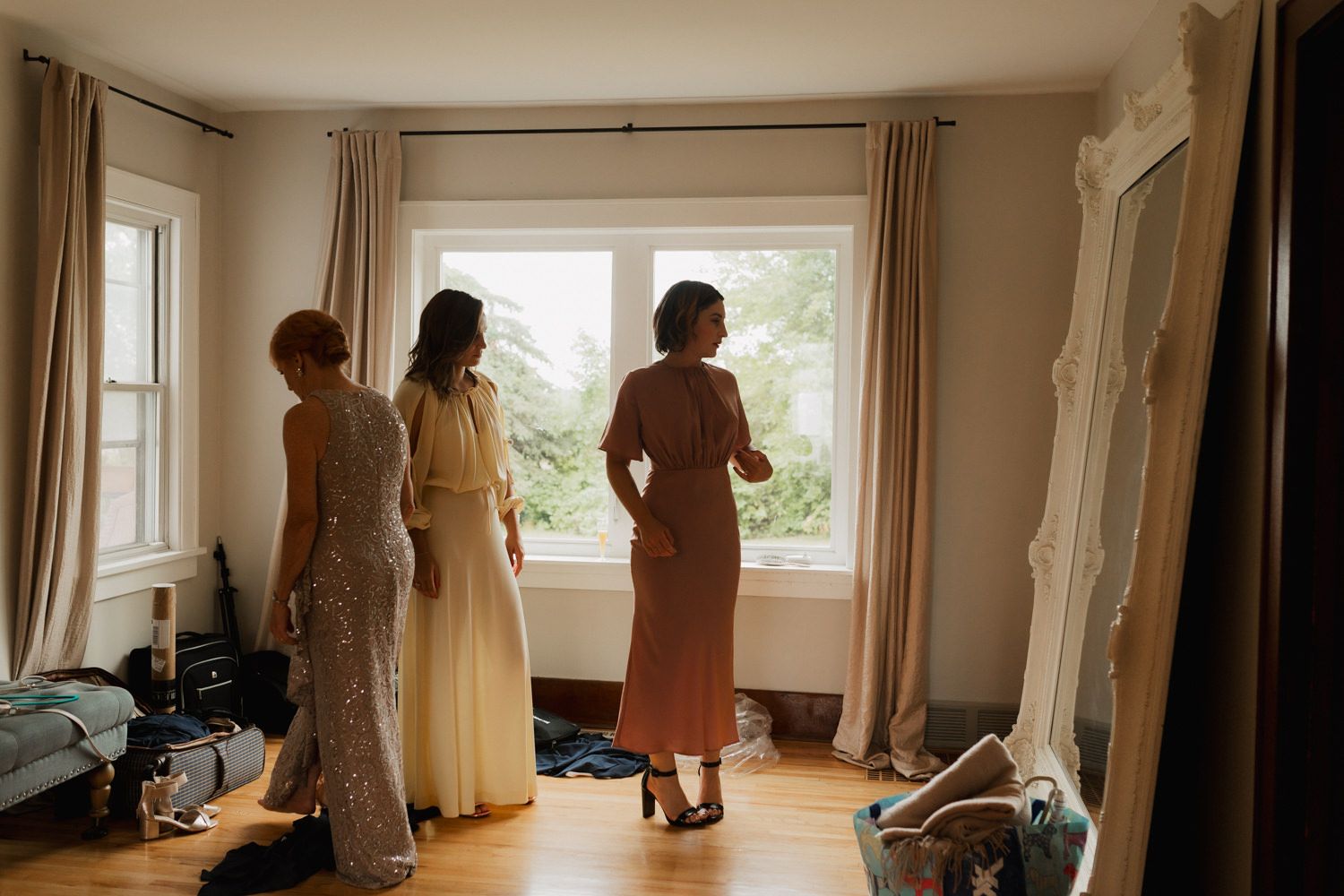 Wedding dress fitting session with multiple gowns displayed in a bright sunlit room with large windows.