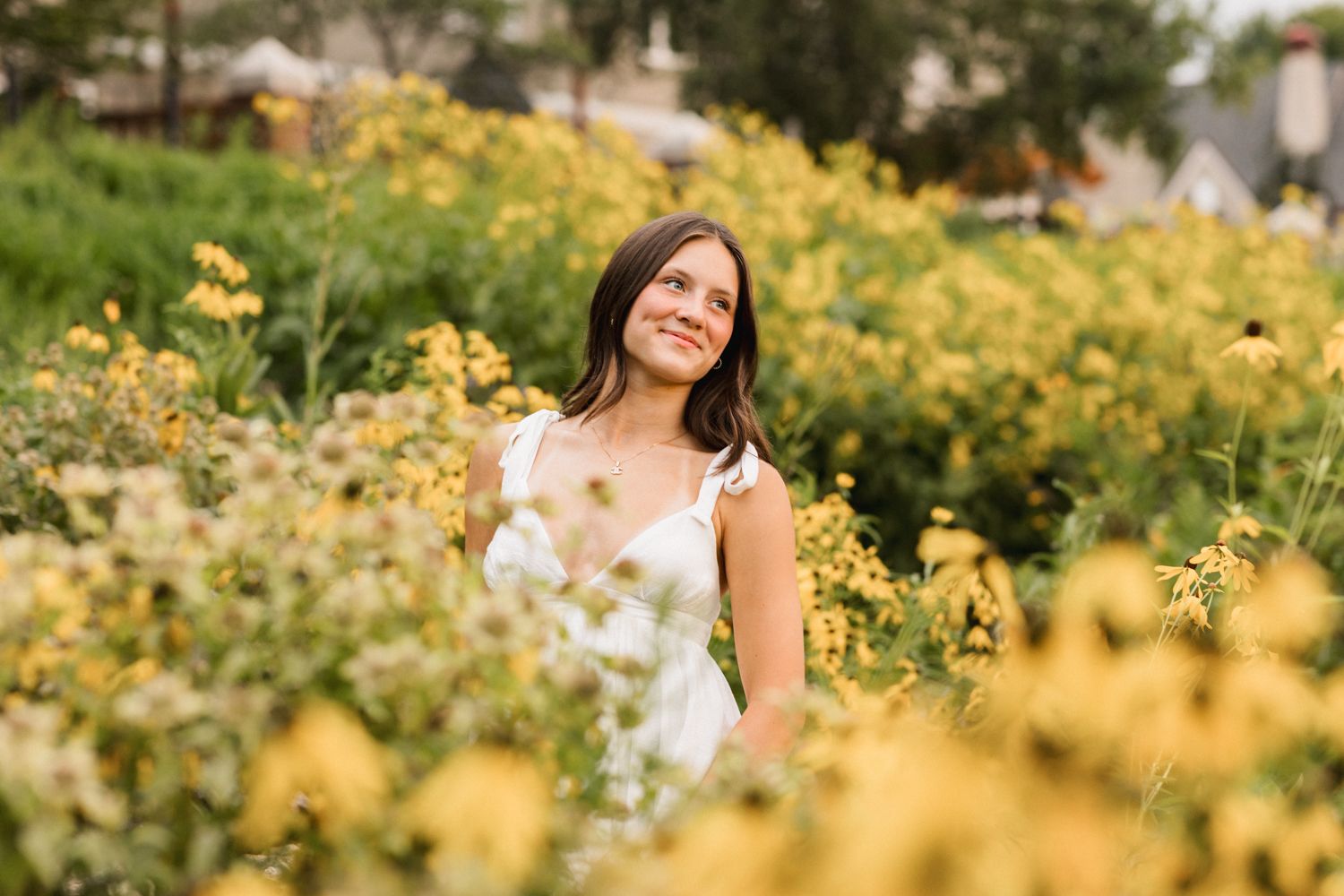 A serene summer portrait surrounded by blooming yellow flowers in a garden setting.