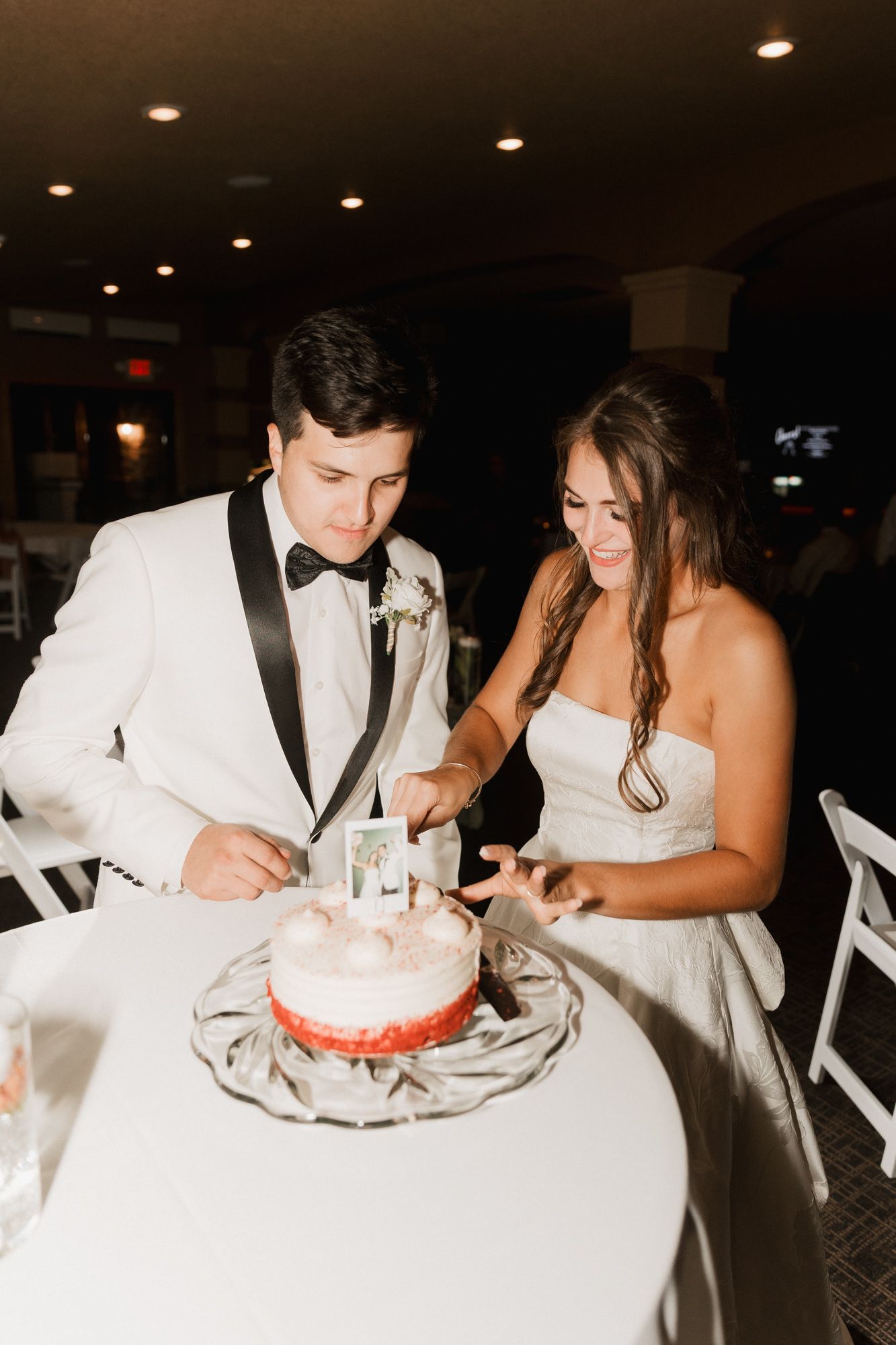 Bride and groom cutting their pink wedding cake together at their reception venue.