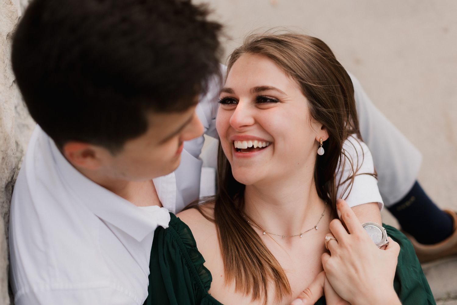 Happy woman laughing with her partner during a romantic engagement photo session outdoors.