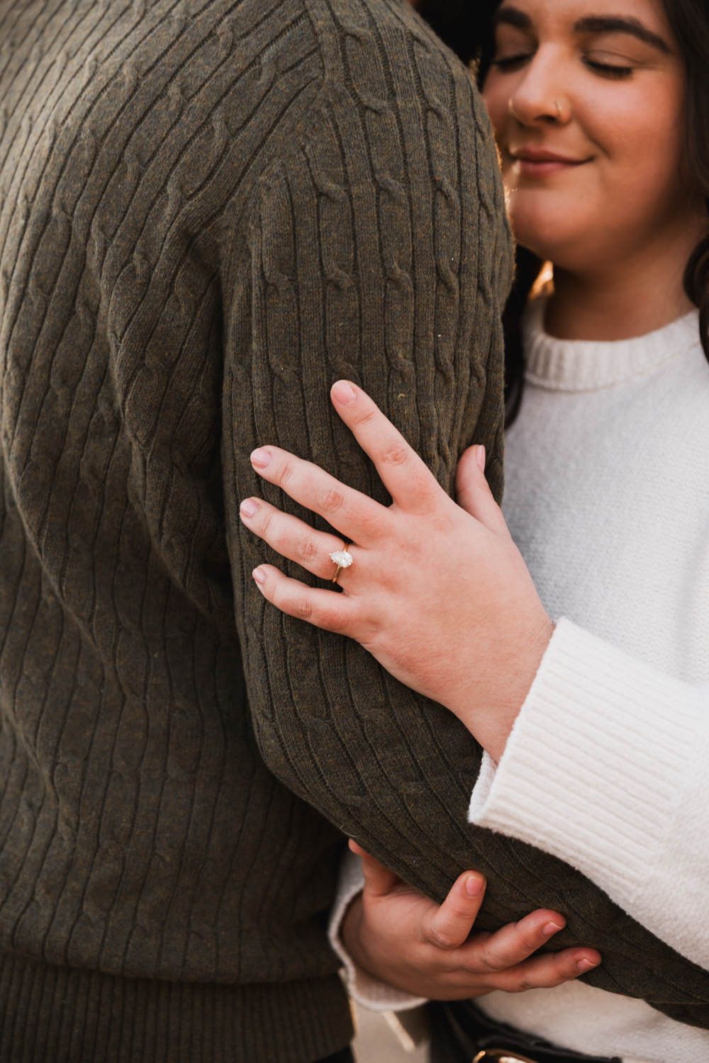 Close-up shots showing hands displaying an engagement ring against a dark sweater background.