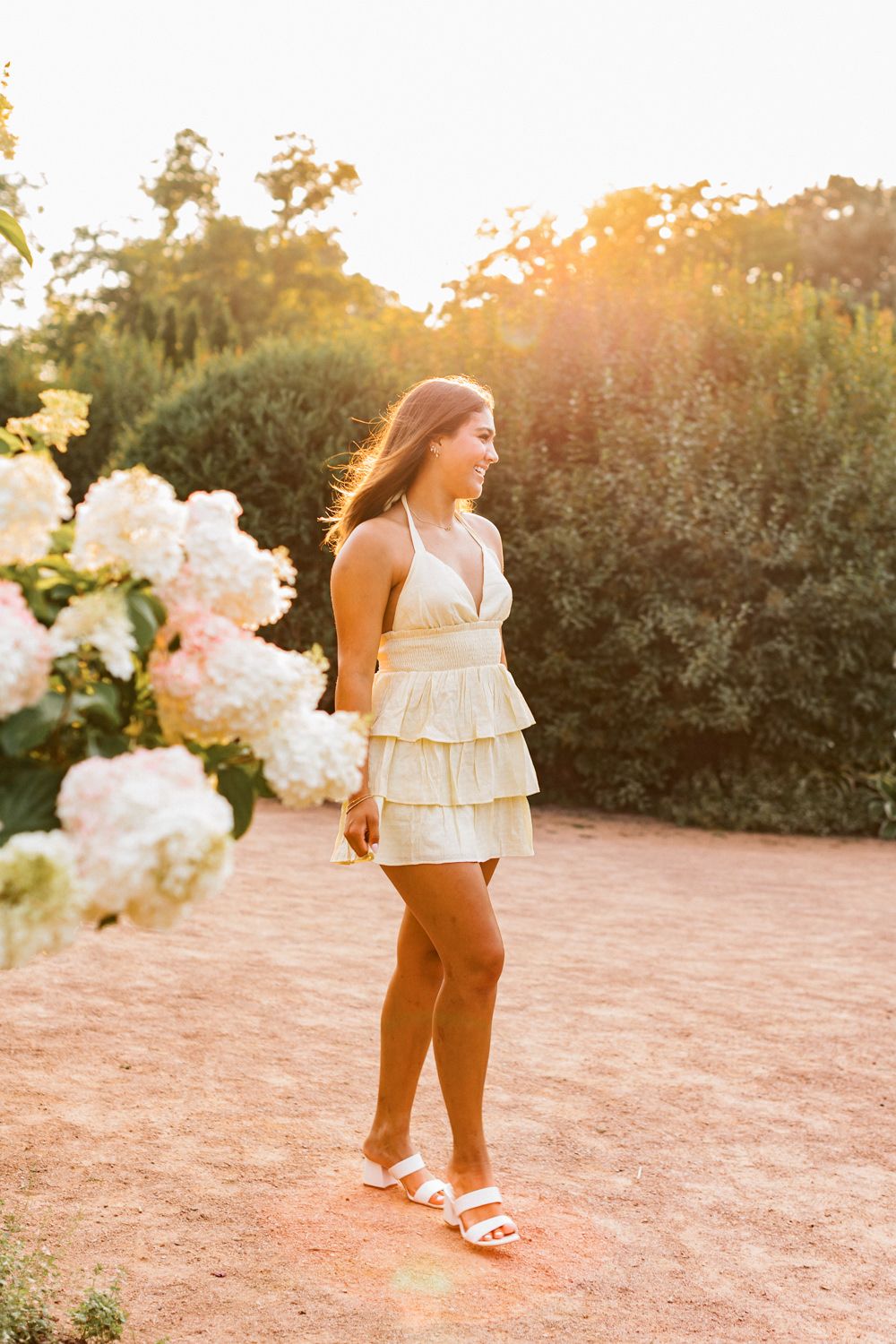 Casual summer photoshoot at sunset featuring yellow ruffled top and white sandals.