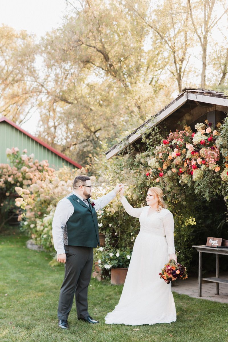 Romantic wedding photography session captured in a garden setting with pink roses and a sage green barn.